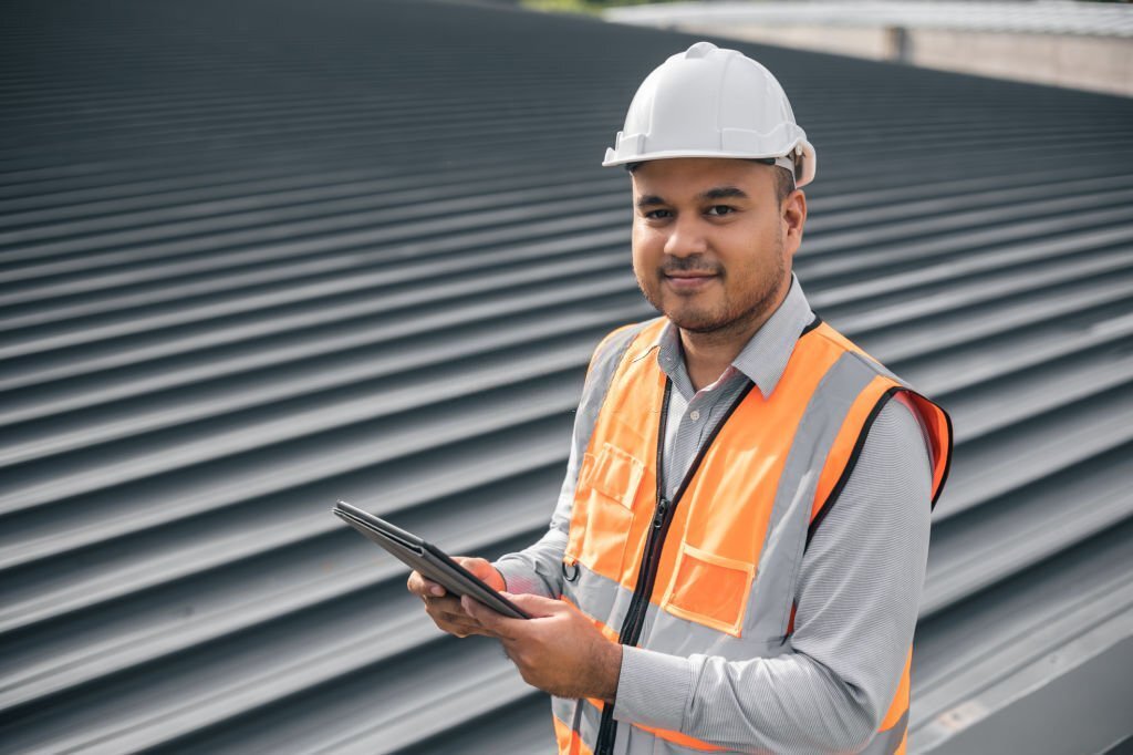 Asian male architect or engineer using tablet control planning construction building. Civil engineers work on the roof of a modern building. Standing on the top floor roof with the sunset